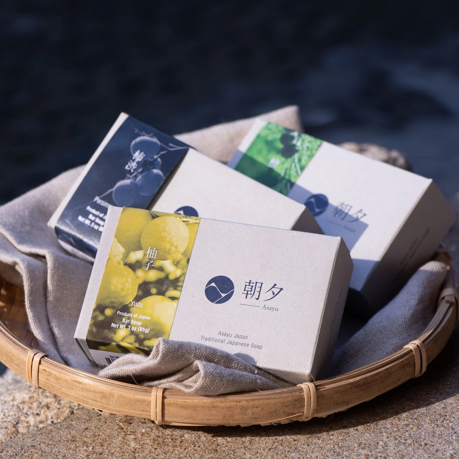 Assorted boxes of soap on a woven tray with a blurred natural background