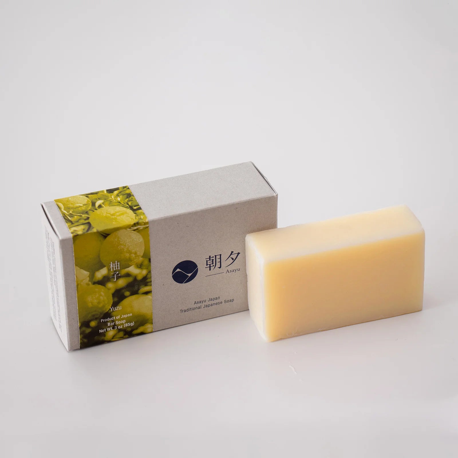 Bar of soap next to its packaging on a light gray background