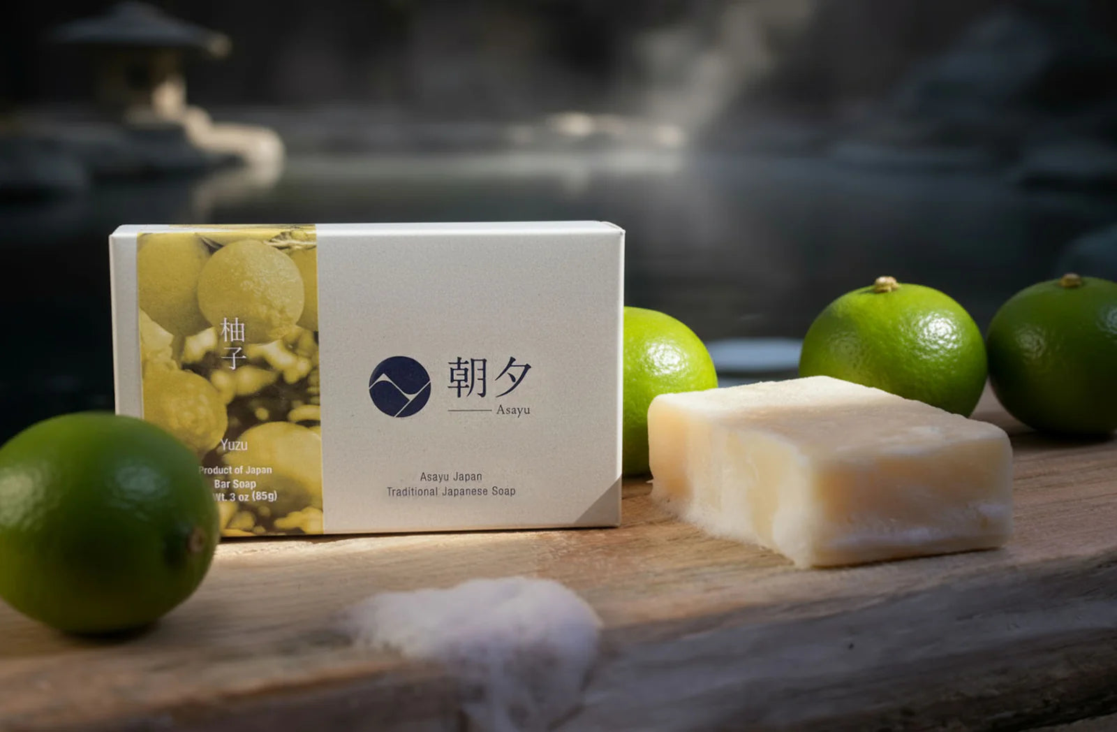 Bar of soap with packaging and limes on a wooden surface